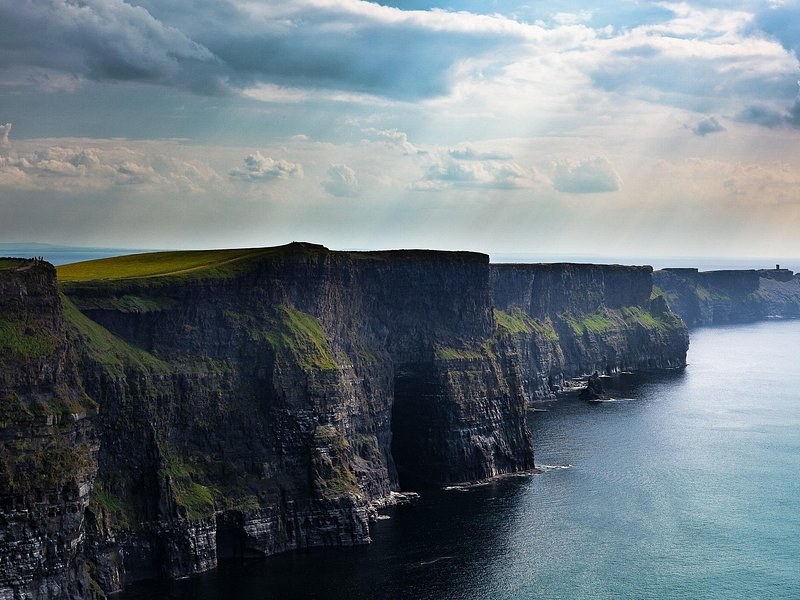 The Cliffs of Moher wall under grey cloud, the grass running right to the edge