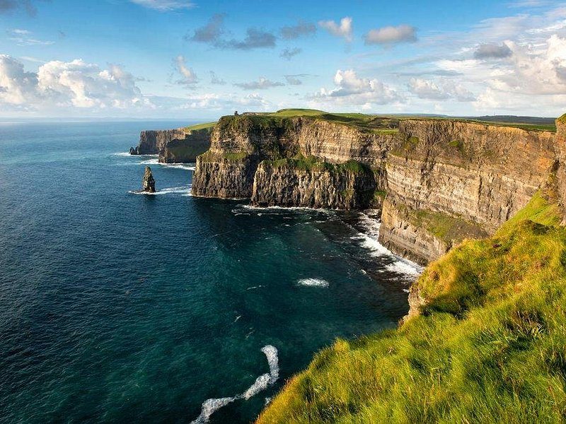 The Cliffs of Moher running north, with a sea stack standing off the foot of the wall