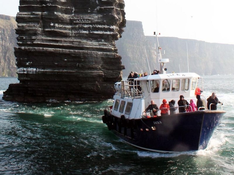A cruise boat at the base of the Cliffs of Moher, dwarfed by the wall above it